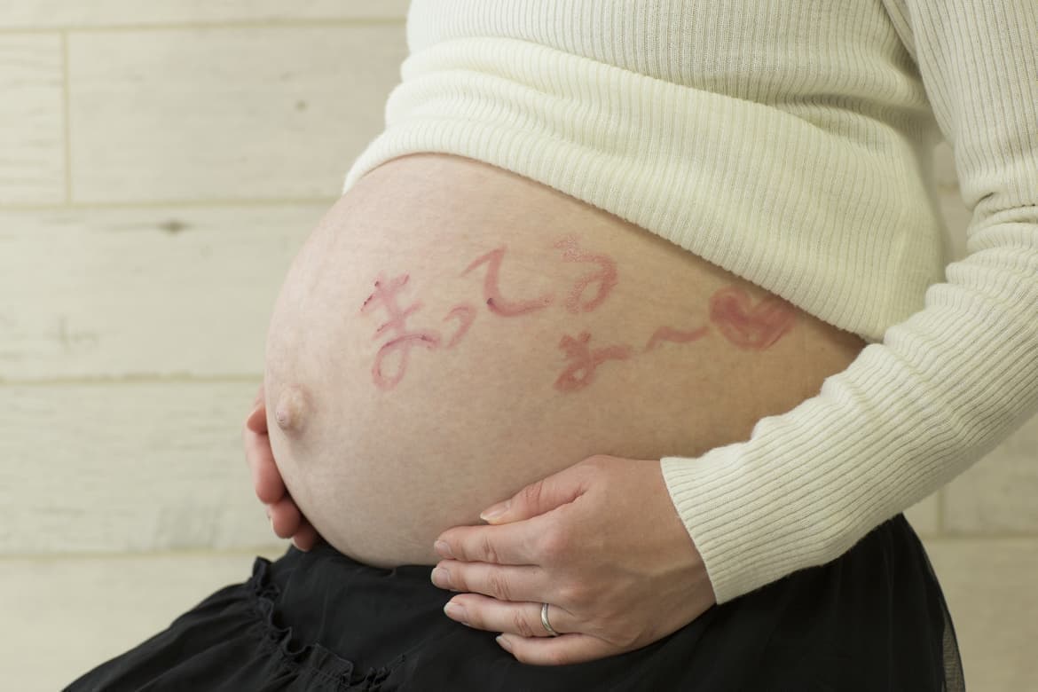 お腹に文字を書いている妊婦さん